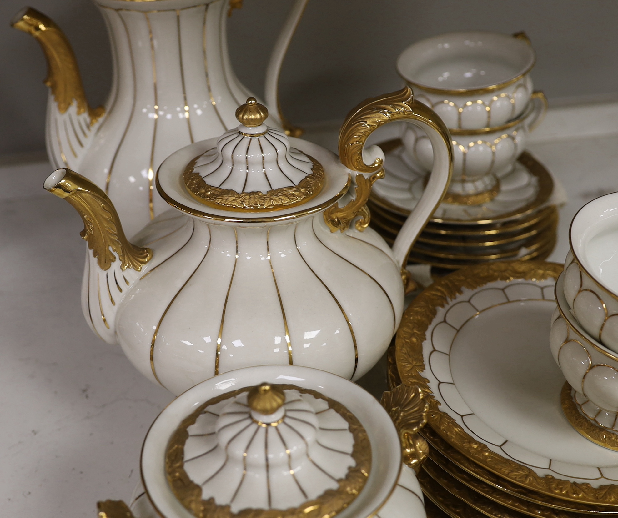 A Meissen gilt and white glazed porcelain tea service, mid 20th century, comprising a teapot, coffee pot, sugar bowl, side plates and seven cups and saucers, coffee pot 28cm